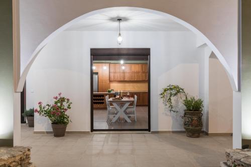 un arco que conduce a una cocina con mesa en Casa Arches, Rhodes en Archipolis