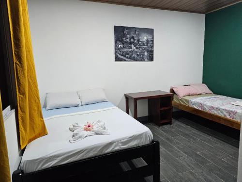 a bedroom with two beds and a table with a flower on it at Hostal Mamá Derlys in Moyogalpa