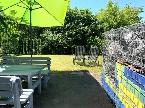 una mesa y sillas con una sombrilla y una valla en Gemütliche Wohnung in Bullay mit Grill, Garten und Terrasse - unikum-Ferienwohnung Perle-Lollipop, en Bullay