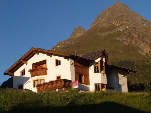een huis op een heuvel met een berg op de achtergrond bij Ferienwohnung in Galtür mit Kleiner Terrasse in Galtür