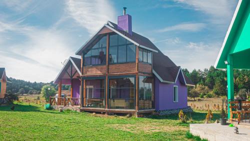una casa con techo de gambrel en un campo verde en Karaçam & Yedigöller doğa evleri, en Kemaller