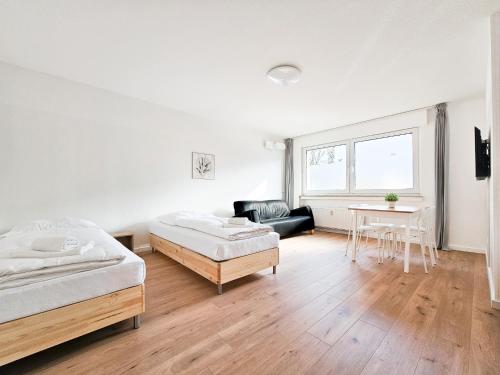 biały pokój z 2 łóżkami i stołem w obiekcie RAJ Living - 2 or 3 Room Apartments - 15 Min zur Messe DUS & 10 Min Old Town DUS w mieście Düsseldorf