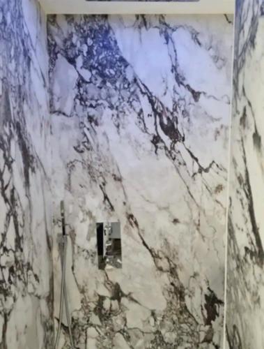 La salle de bains est pourvue d'un mur en marbre. dans l'établissement Love Room stéphanoise, à Saint-Étienne