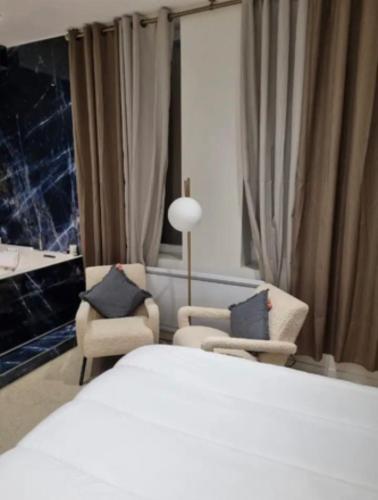 une chambre d'hôtel avec un lit et deux chaises dans l'établissement Love Room stéphanoise, à Saint-Étienne