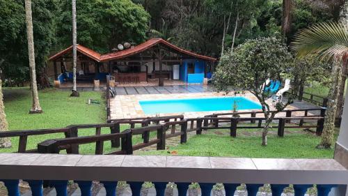 a house with a swimming pool in a yard at Casa de campo agradável com piscina, parquinho, lago, riacho, quadra, sinuca e mais! in Juquitiba