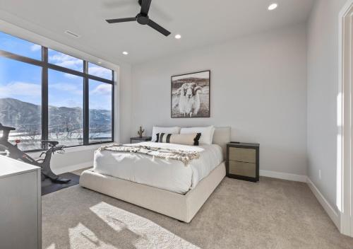 a white bedroom with a bed and a large window at Mountain House PC in Keetley