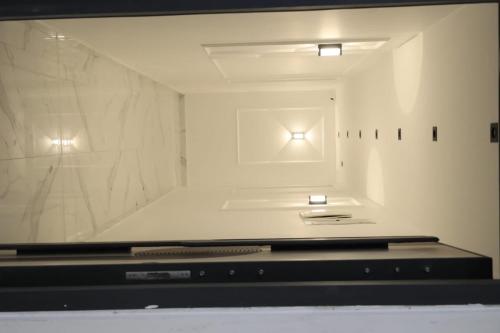 um quarto com uma televisão e uma parede branca em لوكاندة الحصري أكتوبر motel elhosary em Cidade 6 de Outubro
