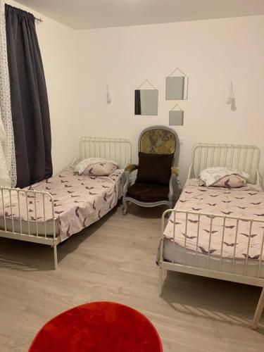 two beds in a room with a red carpet at la maison bel air in Limoux