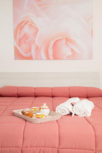 a pink couch with a tray of food and towels at Villa delle Rose Pompei nuova gestione in Pompei