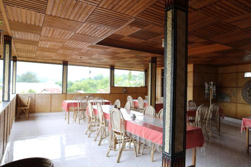 a dining room with tables and chairs and windows at Monton Guest House in Rantepao