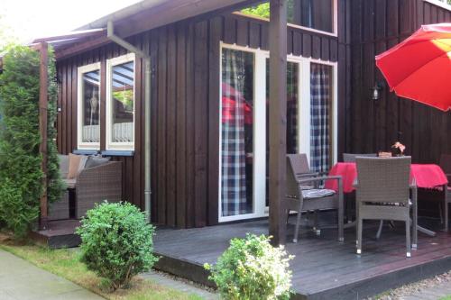 a wooden deck with a table and a red umbrella at Sehr schönes Ferienhaus auf eingezäunten Grundstück mit Kamin und einer Sauna in Extertal