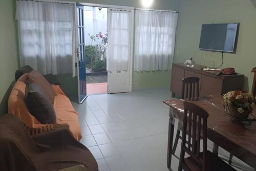 a living room with a couch and a table and a television at Casa Azul in Rio das Ostras