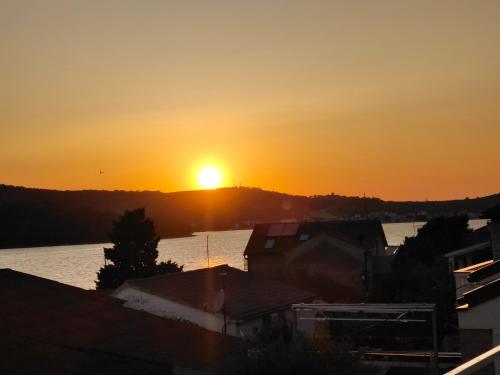 a sunset over a body of water with the sun setting at nautic world studio in Tisno