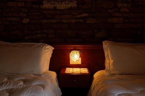 two beds in a room with a light between them at Hotel Pashai in Gjirokastër