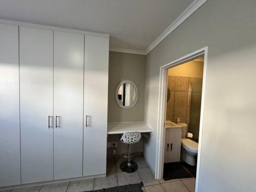 een badkamer met een wastafel, een toilet en een spiegel bij Die Mossienes in Windhoek