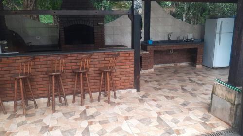 a bar with stools in front of a brick wall at Casa de campo agradável com piscina, parquinho, lago, riacho, quadra, sinuca e mais! in Juquitiba