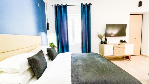 sypialnia z łóżkiem z niebieskimi zasłonami i telewizorem w obiekcie OASIS RESIDENCE w mieście Korynt
