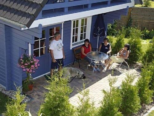 a group of people sitting outside of a blue house at Stolpseehäuser Himmelpfort - Urlaub bei Freunden in Fürstenberg-Havel