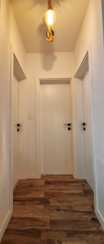 a hallway with two white doors and wood floors at Apartman Barry in Primošten
