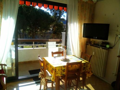 une salle à manger avec une table et un balcon avec une télévision dans l'établissement Studio Petite Provence vacances ou cure vue montagne, à Amélie-les-Bains-Palalda