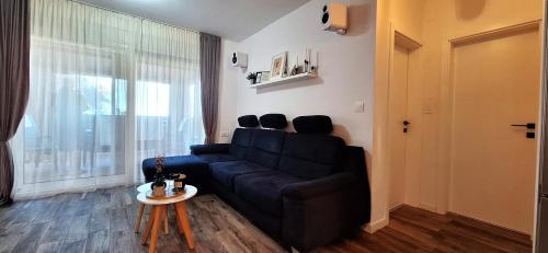 a living room with a black couch and a window at Apartman Barry in Primošten