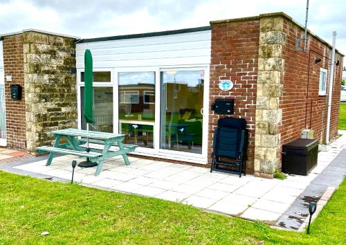 a picnic table in front of a building at CHINE COTTAGE self-catering coastal bungalow in rural West Wight in Freshwater