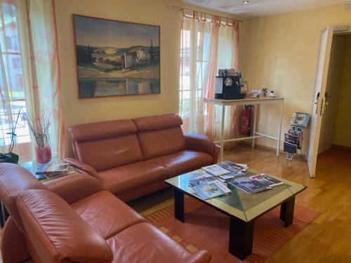 a living room with a leather couch and a coffee table at Auberge de Gilly SA in Gilly