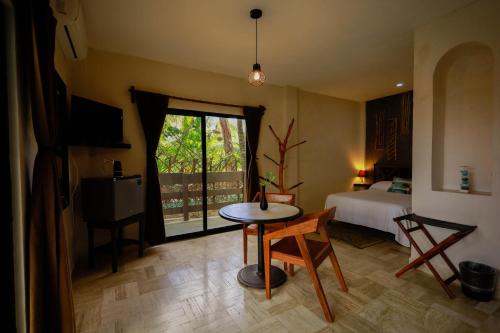 a room with a table and a bed and a window at Hotel Villas Tiburon in Holbox Island