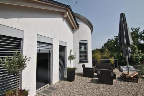 a patio with an umbrella and a chair and an umbrella at Schöne Ferienwohnung in Sasbach Am Kaiserstuhl mit Grill und Terrasse in Sasbach am Kaiserstuhl