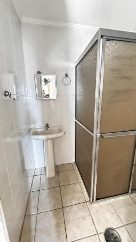 La salle de bains est pourvue d'une douche et d'un lavabo. dans l'établissement Vila Mirim - Mendes House, à Praia Grande