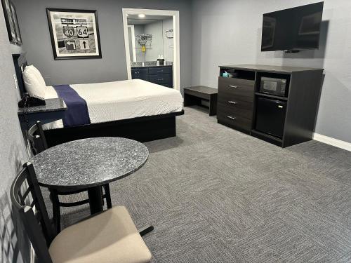 Habitación de hotel con cama, mesa y TV. en Interstate Inn en Roland