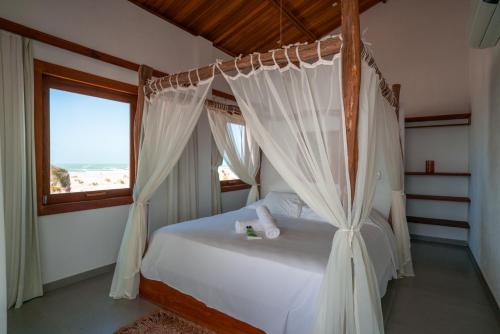 a bedroom with a canopy bed with a window at Maale Caraúbas in Camocim