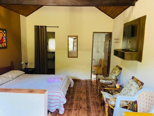 a bedroom with a bed and chairs in a room at Cachoeira do Roncador in São Francisco Xavier