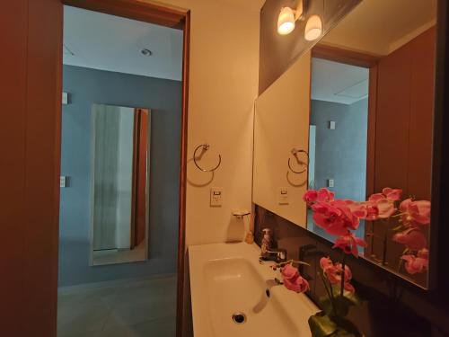 a bathroom with a sink and a mirror and pink flowers at Acogedor y hermoso estudio en la mejor ubicación de Playa! By Yeah in Playa del Carmen