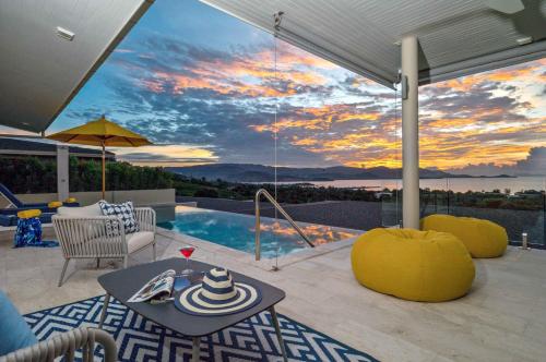 a patio with a table and a pool with a sunset at Sunset Estates - Samui Luxury Villas in Choeng Mon Beach