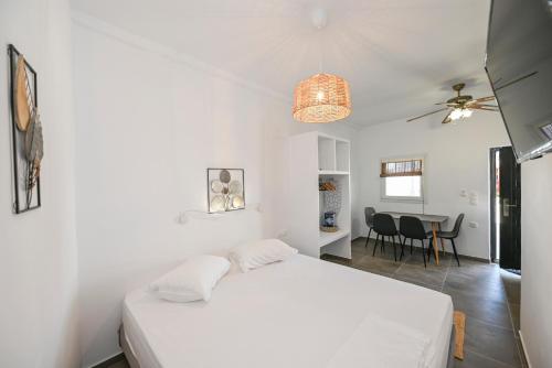 a bedroom with a white bed and a dining room at kleris apartment 10 in Tinos