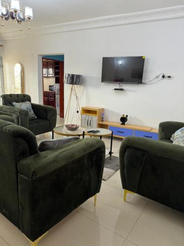 a living room with couches and a tv on the wall at Lekker Estate in Yaoundé