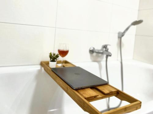 a laptop and a glass of wine on a wooden tray in a bathroom at BackHome - Fantastische Schlosslage, SmartTV, Netflix, 70qm, 24h Checkin - Apartment 2 in Ludwigsburg