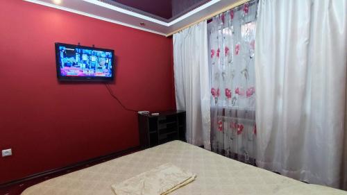 a bedroom with a bed and a tv on a red wall at Apartment on Sportivnaya in Bender