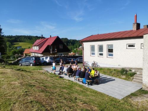 un grupo de personas sentadas sobre sillas frente a un edificio en Penzion U Lipna, en Přední Výtoň