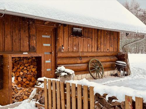 a wooden cabin with a wooden wheel in the snow at Dřevěný romantický srub v Krušných horách in Hroznětín
