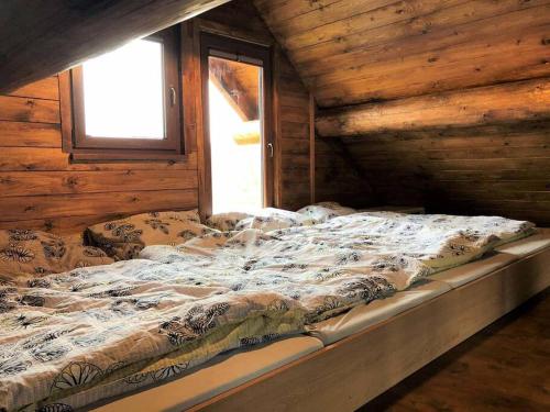a large bed in a log cabin with a window at Dřevěný romantický srub v Krušných horách in Hroznětín
