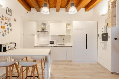カリアリにあるSuite Martini al Castelloの白いキャビネット、テーブルと椅子付きのキッチンが備わります。