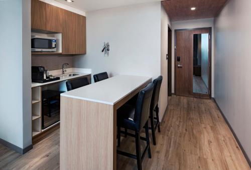 a kitchen with a counter and chairs in a room at AC Hotel by Marriott San Jose Escazu in San José