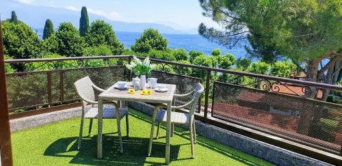 een tafel en stoelen op een balkon met uitzicht op de oceaan bij Mini-Penthouse Attico Bianca in San Felice del Benaco