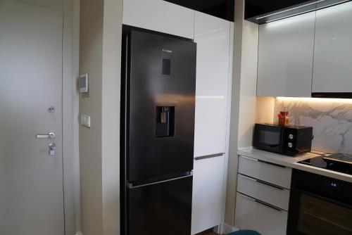 a black refrigerator in a kitchen with white cabinets at Diamond 72 apartment , Skopje City - Center, Diamond Residences, free parking in Skopje