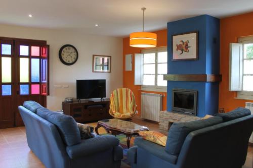 a living room with blue chairs and a fireplace at Casa de Aldea Monga 9 en Nava, Asturias in Nava