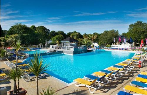 une grande piscine avec des chaises longues jaunes dans l'établissement Domaine de Kerlann - Mobilhome refait à neuf- 40m2 - service de conciergerie et lits faits OFFERTS, à Pont-Aven