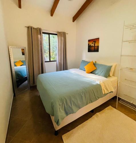1 dormitorio con 1 cama con almohadas azules y amarillas en TRANQUILA CASA DE PLAYA, en Santa Cruz