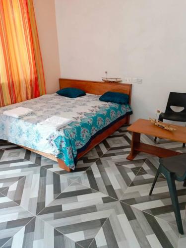 ein Schlafzimmer mit einem Bett, einem Tisch und einem Schreibtisch in der Unterkunft Palm Grove lodge in Busua